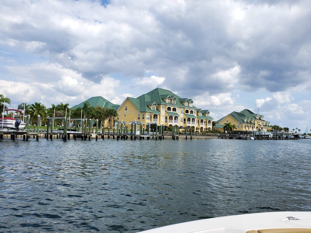 Homes and boat docks across a wide canal under a partly cloudy sky