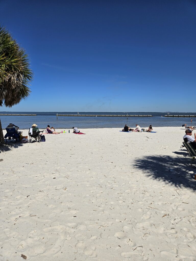 A wide white sand beach with a pier in the distance on the Florida Gulf Coast