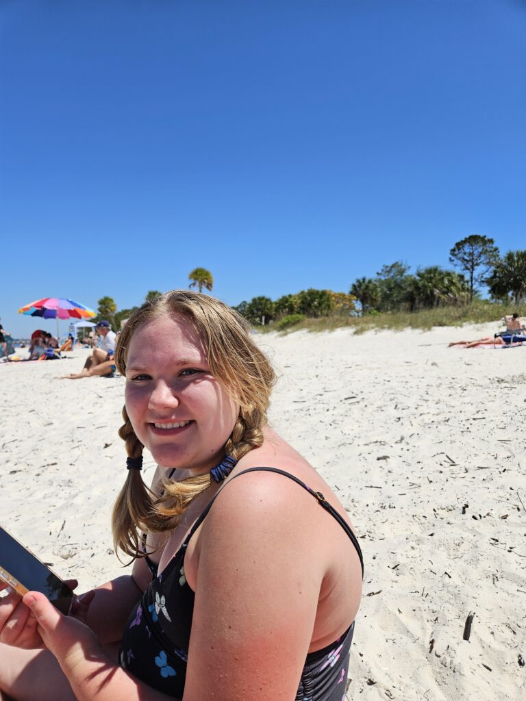 A woman smiling on a white sand Florida beach on a clear day