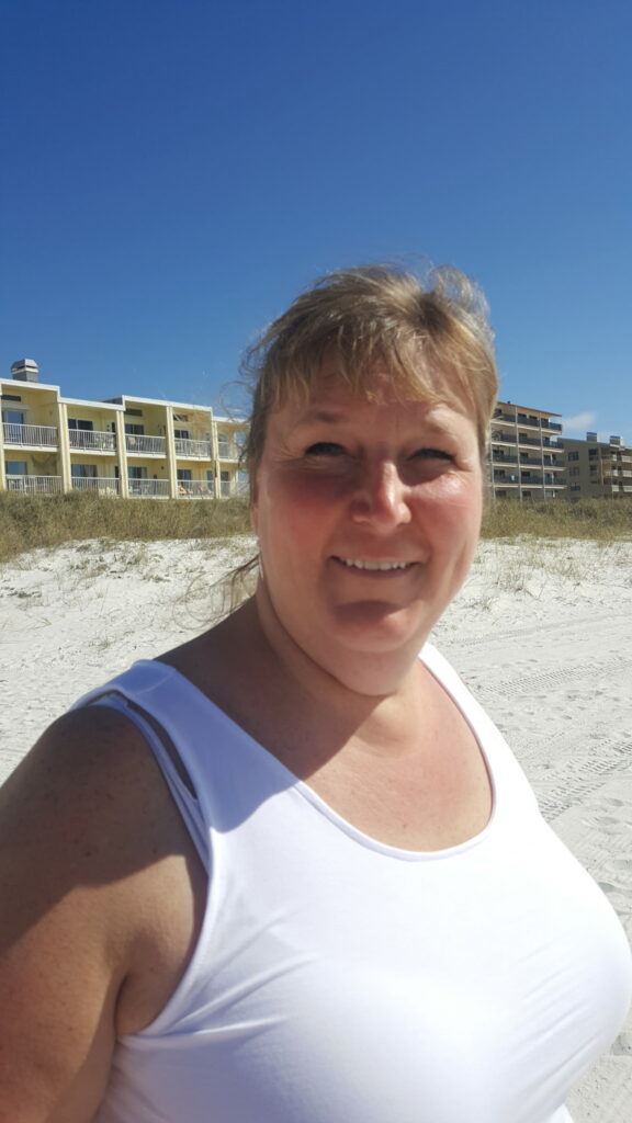 A woman on a Florida beach with resort buildings behind her