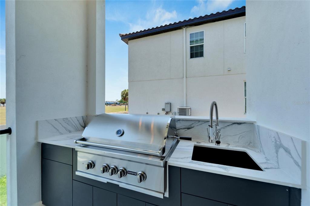Outdoor kitchen with flat-top grill and sink on the lanai at 517 Treviso Drive