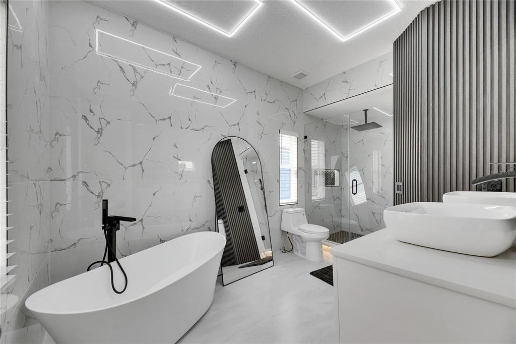 Primary bath with freestanding tub and floor-to-ceiling tile at 6512 Simone Shores Circle
