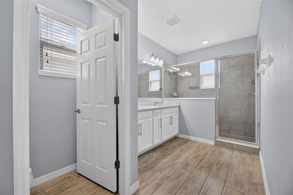 Primary bath with dual stone vanities and tiled shower
