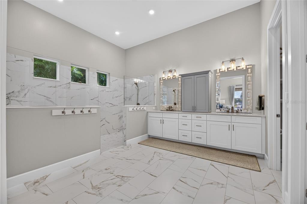 Primary bath with walk-in shower and dual vanities at 825 Manns Harbor Drive
